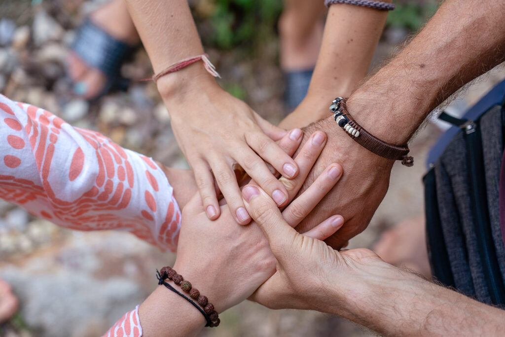 Arm stacked together one by one in unity and teamwork. Many hands getting together in the center of a circle. Close up outdoor shot. Many hands connecting in nature.